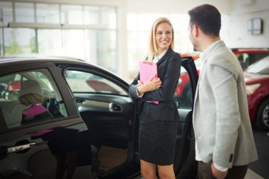 Araç showroom içinde duran güzel genç pazarlamacı portresi