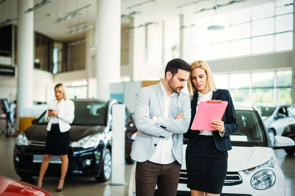 stock image Portrait of beautiful young saleswoman standing inside vehicle showroom