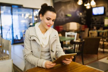 Kafede dijital tablet kullanarak çekici genç kadın