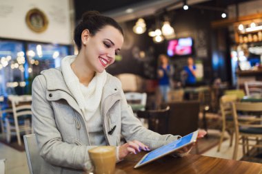 Kafede dijital tablet kullanarak çekici genç kadın