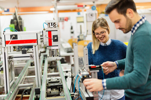 Young attractive students of mechatronics working on project together