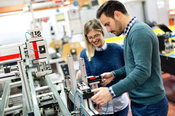 Young attractive students of mechatronics working on project together