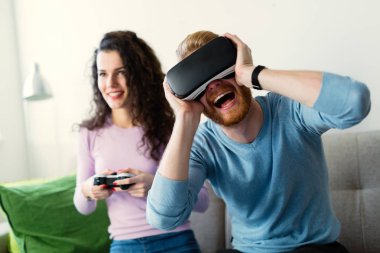 Mutlu genç video oyunları oynarken evde sanal gerçeklik kulaklıklar ile çift.