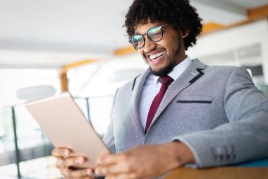 Klasik takım elbiseli yakışıklı Afro-Amerikan iş adamı dijital tablet kullanıyor.