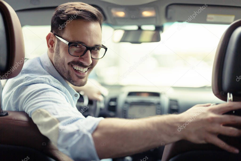 Handsome smart businessman driving a car to work