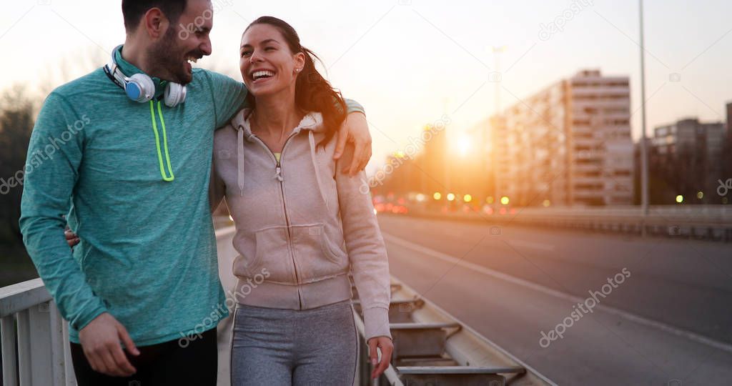 Young attractive and cheerful couple running outside on sunny day