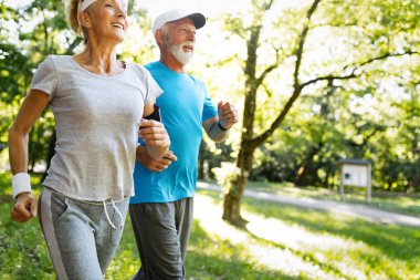 Kadın kıdemli ve koşan adam açık fitness egzersizleri yapıyor