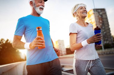 Kadın kıdemli ve koşan adam bir şehirde fitness egzersizleri yapıyor
