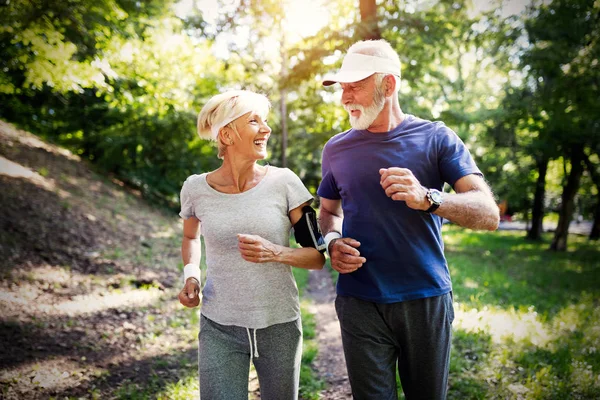 Senior couple jogging and running outdoors in park nature