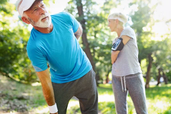 Senior man having a back pain during sport in a park