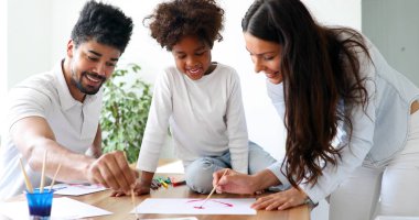 Anne ve baba evde çocuklarıyla birlikte resim çiziyorlar.