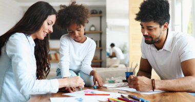 Anne ve baba evde çocuklarıyla birlikte resim çiziyorlar.