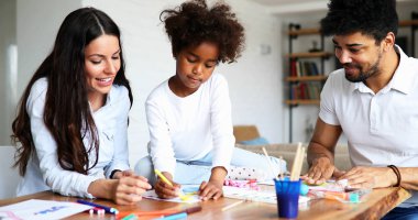Anne ve baba evde çocuklarıyla birlikte resim çiziyorlar.