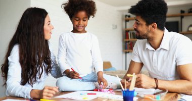 Anne ve baba evde çocuklarıyla birlikte resim çiziyorlar.