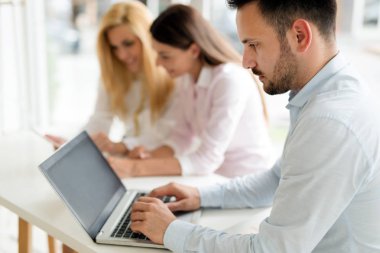 Modern ofis içinde bilgisayar üzerinde çalışan genç iş adamları