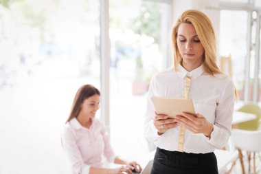 Tablet tutan genç güzel gülümseyen uzun saçlı sarışın kadın portresi