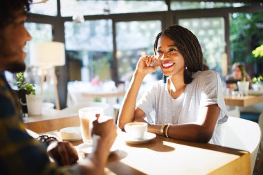 Bir kafede kahve içme ve birlikte iken bir tarih üzerinde konuşurken bir masada oturan genç Afrikalı çift gülümseyen