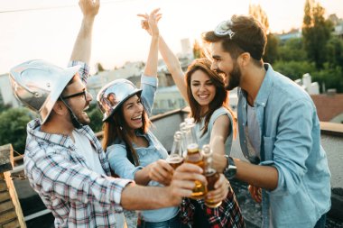 Bir grup mutlu genç arkadaş çatıda parti veriyor.