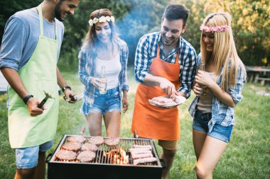Neşeli arkadaşlar doğada vakit geçirip barbekü yapıyorlar.