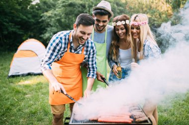 Neşeli arkadaşlar doğada vakit geçirip barbekü yapıyorlar.