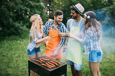 Neşeli arkadaşlar doğada vakit geçirip barbekü yapıyorlar.