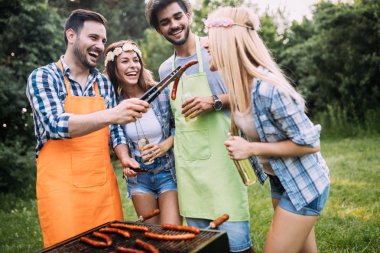 Neşeli arkadaşlar doğada vakit geçirip barbekü yapıyorlar.