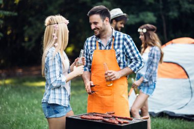 Neşeli arkadaşlar doğada vakit geçirip barbekü yapıyorlar.