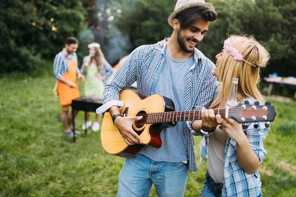 Stilig man spela gitarr till sin flickvän i naturen — Stockfoto