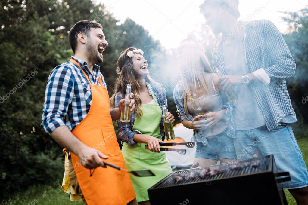 Cheerful friends spending time in nature and having barbecue