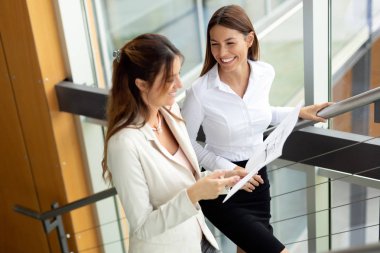 Modern ofis lobisinde iş adamları belgeler üzerinde tartışıyor..