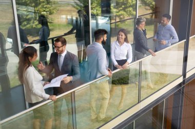Modern ofis lobisinde iş adamları belgeler üzerinde tartışıyor..