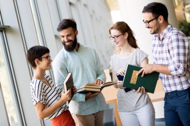 Grup öğrenci üniversite kitaplığında tartışıyor