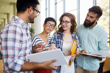 Mutlu genç üniversite öğrencileri ile kütüphane kitaplarında. Bir grup üniversite kitaplığında çok ırklı insan.