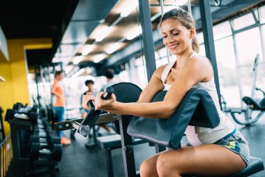 Genç güzel kadın için spor salonunda pazı egzersizleri yapıyor