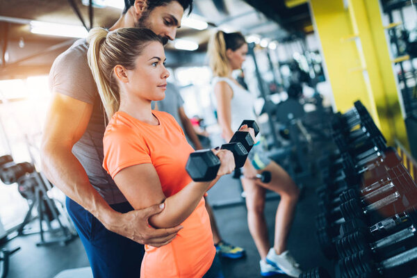 Personal trainer giving instructions to student in gym