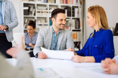 Genç ve mutlu iş adamları ofiste beyin fırtınası yapıyor.