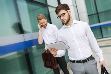 Açık havada yürüyüş ve kullanarak iş adamları telefonları Tablet