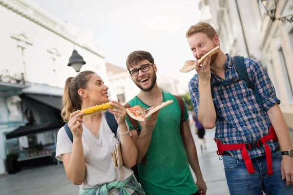 Mutlu insanlar sırt çantaları ile seyahat ederken şehirde hızlı yemek yeme