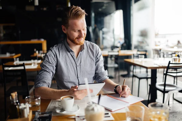 Businessman taking notes and writing down new ideas in cafe during break