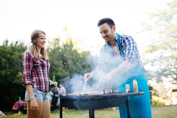 幸せな友人は肉を焼くと屋外でバーベキューパーティーを楽しむ — ストック写真