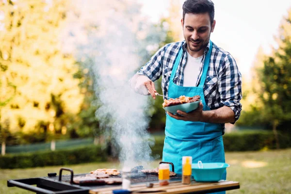 自然の屋外バーベキューの肉を焼く幸せな男性 — ストック写真