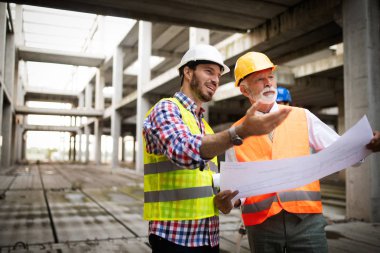 Mimarlar ve mühendislerden oluşan kendinden emin bir ekip modern inşaat alanında birlikte çalışıyor.