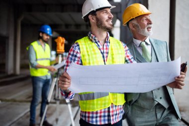 Mimarlar ve mühendislerden oluşan kendinden emin bir ekip modern inşaat alanında birlikte çalışıyor.