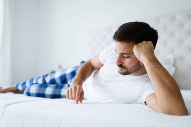 Yatakta yatarken genç mutsuz adam portresi