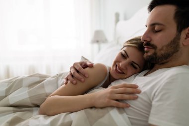 Genç çekici mutlu çift yatakta romantik vakit geçiriyor