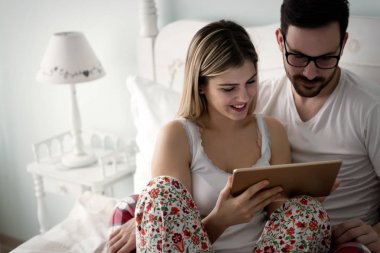 Genç çekici çift yatak odasında dijital tablet kullanma