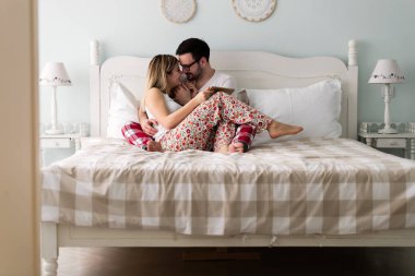 Genç çekici çift yatak odasında dijital tablet kullanma