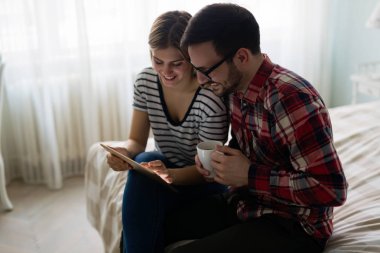 Genç çekici çift yatak odasında dijital tablet kullanma