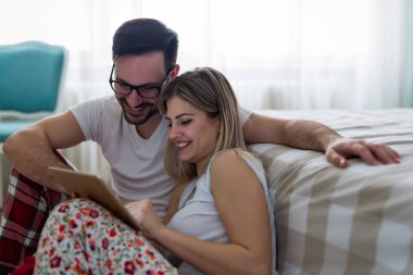 Genç çekici çift yatak odasında dijital tablet kullanma