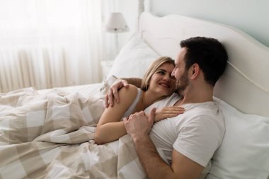 Genç çekici mutlu çift yatakta romantik vakit geçiriyor